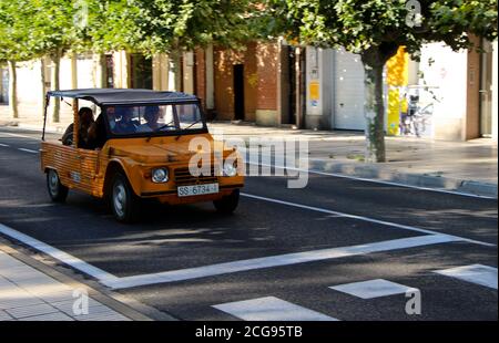 Arancione luminoso, apertura in alto, Citroen Mehari, SUV compatto fuoristrada Guidato lungo una strada alberata Palencia Castiglia e Leon Spagna ha registrato San Sebastian Foto Stock