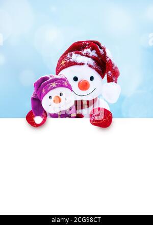 Due piccoli pupazzi di neve la ragazza e il ragazzo in cappelli e sciarpe sulla neve in inverno. Sfondo di festa con un divertente pupazzo di neve. Scheda di Natale, copia dello spazio. Foto Stock