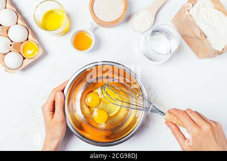 Le mani della donna che tengono le uova a sussurro in una ciotola di metallo Foto Stock