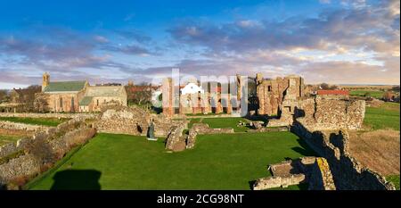 Le rovine romaniche dell'abbazia di Lindisfarne, sassone, che si affaccia sul castello di Lidisfarne, sull'isola Santa, su Lindisfarne, su Northumbria, in Inghilterra Foto Stock