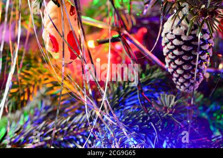 Una tinella d'argento sull'albero di Natale. Sfondo di vacanza Blured con ghirlanda, giocattoli in vetro, palline, luci. Decorazione colorata primo piano. Foto Stock