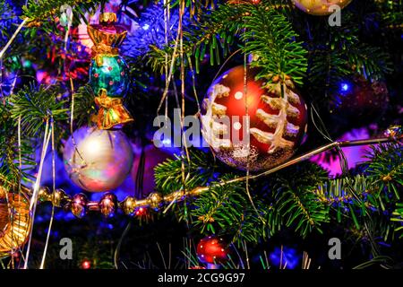 Una tinella d'argento sull'albero di Natale. Sfondo di vacanza Blured con ghirlanda, giocattoli in vetro, palline, luci. Decorazione colorata primo piano. Foto Stock