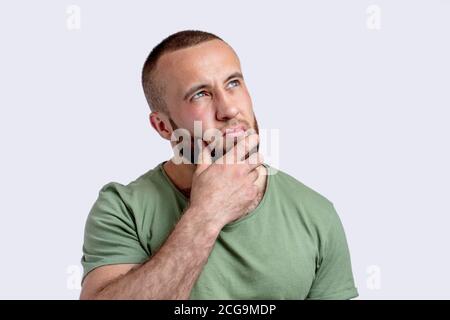 Uomo adulto caucasico penciva con barba che pensa dubitare e meditare, lavorando fuori la decisione, tenendo la mano vicino al mento e guardando da parte, isolato o Foto Stock