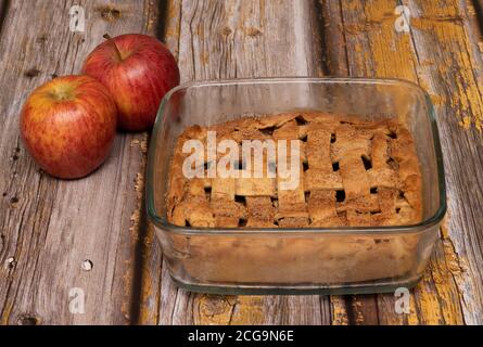 Forno torta di mele cotta in una casseruola di vetro sopra uno sfondo di legno Foto Stock