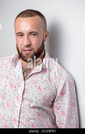 Ritratto di Capo d'azienda con un aspetto serio e con un taglio corto e una complicazione atletica, elegantemente vestito in camicia bianca con stampa floreale Foto Stock