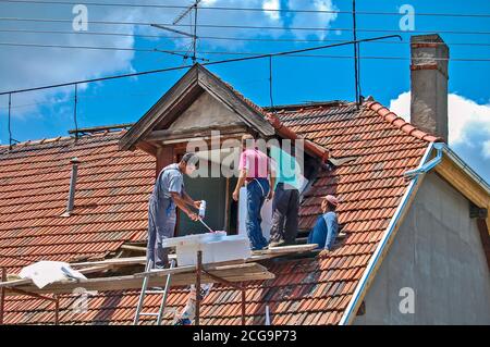 Zrenjanin, Serbia, 17 luglio 2013. Un gruppo di artigiani sta lavorando sul tetto e bella stirofoam sui lati della finestra sporgente del ter Foto Stock