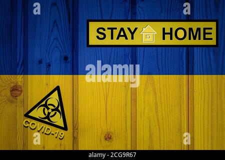 Bandiera dell'Ucraina in proporzioni originali. Quarantena e isolamento - soggiorno a casa. Bandiera con simbolo di rischio biologico e iscrizione COVID-19. Foto Stock