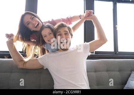 Felici genitori allegri che si divertono con le figlie carine che giocano sul divano Foto Stock