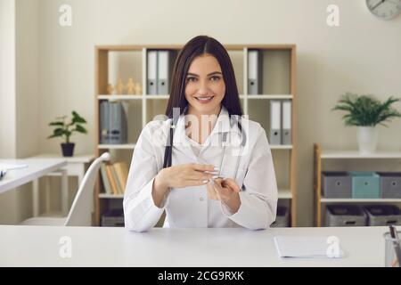 Dottore femminile che guarda la fotocamera e parla mentre conduce una consultazione in linea. Foto Stock