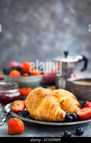 Colazione continentale con croissant, frutti di bosco freschi, caffè e marmellata, sfondo grigio Foto Stock