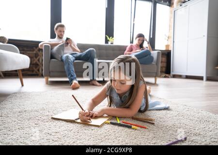 Ragazza carina di capretto che gioca sul pavimento, disegno della ragazza piccola prescolare con matite colorate sulla carta che passa il tempo con la famiglia Foto Stock