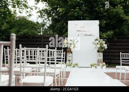 Cerimonia nuziale esterna. Arco da matrimonio bianco e sedie per gli ospiti Foto Stock