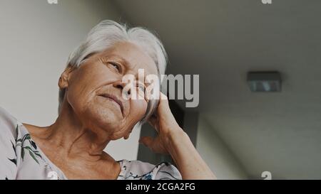 Ritratto di donna anziana con capelli grigi che guarda in lontananza. Scatto ad angolo basso. Foto di alta qualità Foto Stock