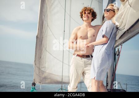 Giovane coppia caucasica in amore relax su yacht prow, godendo di sole giorno e fresco vento di mare, esclusivo concetto di stile di vita in viaggio Foto Stock