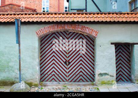 vecchio vintage a strisce rosso e bianco porta di legno in vecchio muro dipinto di mattoni bianchi con tetto rosso nel vecchio Città di Tallinn in Estonia Foto Stock