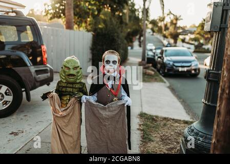 Giovani fratelli vestiti con costumi di Halloween durante Trick-or-Treat Foto Stock