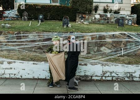 Giovani fratelli vestiti in costumi Trick-or-treating su Halloween Foto Stock