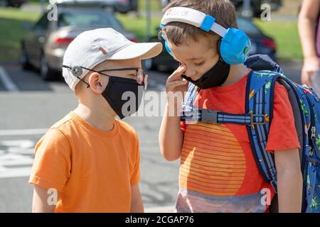 due bambini di 4 anni il primo giorno di ritorno a scuola, maschera facciale indossata Foto Stock