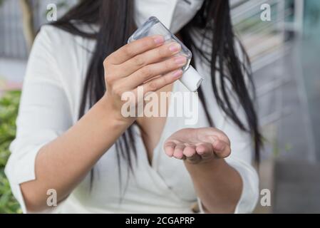 Primo piano, donna Latina che mette gel antibatterico sulle mani mentre indossa una maschera protettiva Foto Stock