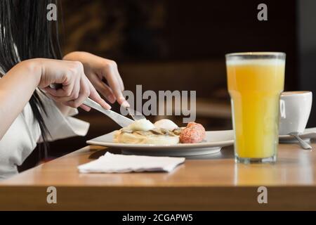 donna che ha la prima colazione in un posto molto luminoso con un succo d'arancia Foto Stock