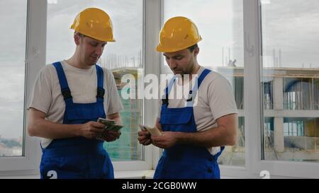 Costruttori in caschi che contano lo stipendio. Foto Stock