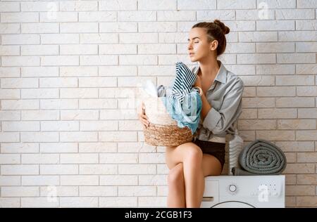 Bella giovane donna sta facendo lavanderia a casa. Foto Stock