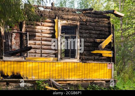 Muro di casa rurale giallo bruciato con finestre vuote e cartello di avvertimento. Testo in russo significa: Infiammabile, bombole di gas Foto Stock