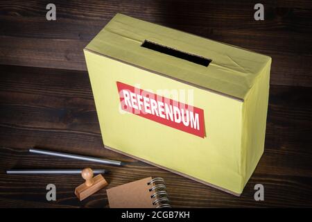 REFERENDUM. Scatola di voto su sfondo di legno. Matite, timbro e blocco note Foto Stock