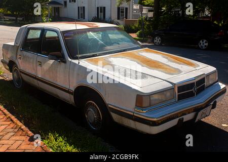 Chestertown, MD, USA 08/30/2020: Vista laterale di una vecchia auto bianca arrugginita Dodge Dynasty LE parcheggiata all'esterno della strada. Ha arrugginito e scheggiato dolore Foto Stock