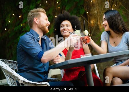 Gruppo di amici diversi che parlano e si divertono al bar all'aperto Foto Stock