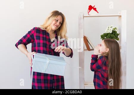 Adorabile bambina con grande scatola regalo che lo dà a sua madre. Lei è presente aperto. Vacanze, compleanno e presenta concetto. Foto Stock