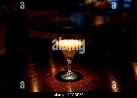 Cocktail di caffè con schiuma bianca al bancone di un bar scuro. Foto Stock