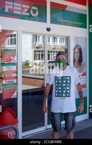 uomo più anziano mascherato in piedi fuori del supermercato che indossa t.shirt di pecora in protesta passiva contro l'uso forzato della maschera viso lenti contea di zala ungheria Foto Stock