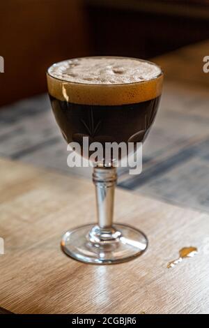 Un bicchiere di birra belga scura è sul tavolo Foto Stock