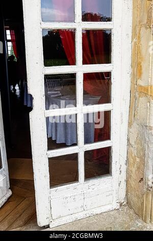 Vecchia porta di legno bianca con vetro in una vecchia casa di pietra. Foto Stock
