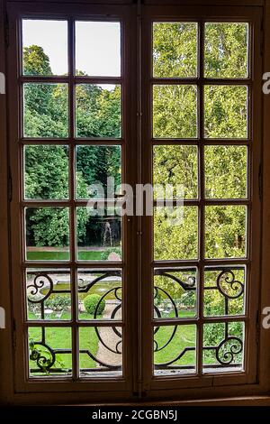 Vista attraverso la finestra con le barre sul parco verde Foto Stock