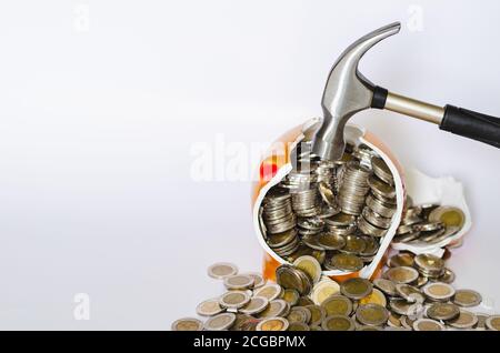 Martello rompendo banca piggy con le monete thailandesi baht su bianco sfondo Foto Stock