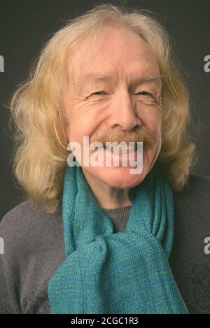 Senior uomo con i baffi contro uno sfondo grigio Foto Stock