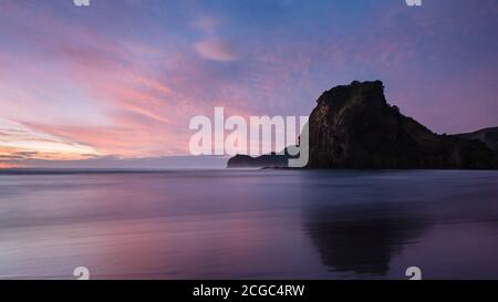 Lion Rock della spiaggia di Piha al tramonto, Waitakere, Auckland Foto Stock