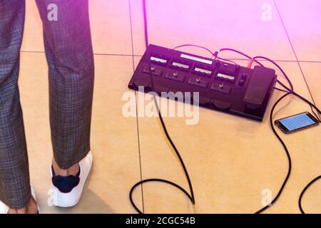 Sul pavimento. C'è un chitarrista nelle vicinanze. Abbiamo avuto le gambe in sneakers e fili. Foto Stock