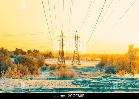 Due pilastri della linea ad alta tensione e fili attraverso la pianura fluviale in inverno. Siberia. Foto Stock