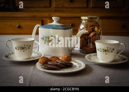 2 tazze da tè in piattini con teiera e recipiente per biscotti Foto Stock