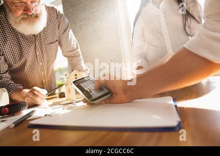 Mani di architetto-ingegnere e giovane coppia durante la presentazione della futura casa. Tabella vista laterale con documenti, blueprint. Primo concetto di casa, industriale, edilizia. Passaggio a un nuovo live place. Foto Stock