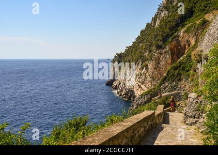 Vista panoramica dalla scogliera che domina il mare ligure con due turisti sul sentiero in pietra in estate, Porto Venere, la Spezia, Liguria, Italia Foto Stock