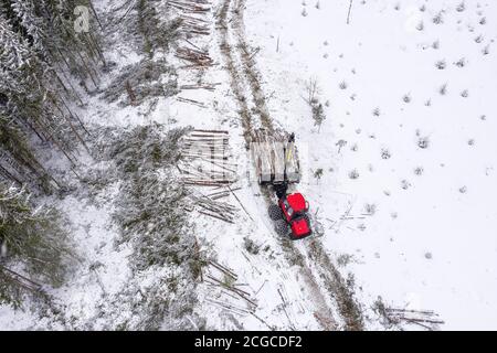 Vendemmia europea di legname di abete rosso in Norvegia durante l'inverno con macchinari pesanti nella neve, colpo di drone dall'alto Foto Stock