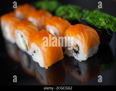 Set di sushi al salmone. Sushi roll Philadelphia con pesce rosso, salmone, caviale rosso. Arrotolare con avocado morbido e formaggio cremoso sotto uno strato di caviale massago Foto Stock