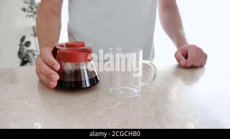 Caffè appena fatto in paniera di vetro e tazza di vetro sul tavolo. Pourover, V60. Foto Stock