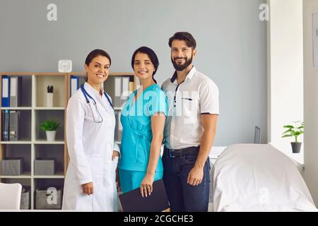 Ritratto di gruppo di tre giovani operatori sanitari sorridenti in moderno studio clinico Foto Stock