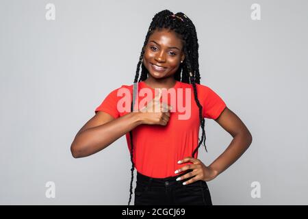 Sorridente giovane donna afroamericana mostra pollici su consiglia buona servizio isolato su sfondo grigio dello studio Foto Stock