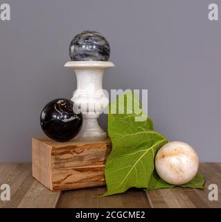 Vaso e palle in marmo su un supporto in legno. Grande foglia verde. Vita morta. Vintage. Foto Stock